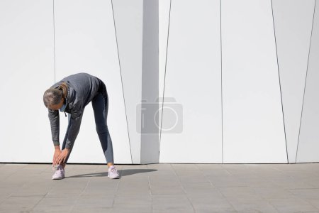 Foto de Estiramiento. Mujer en ropa deportiva ejercitando y haciendo ejercicios para estirar - Imagen libre de derechos