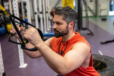 Foto de Muscular fitness hombre haciendo ejercicio con TRX, entrenamiento funcional para el cuerpo en el gimnasio. - Imagen libre de derechos