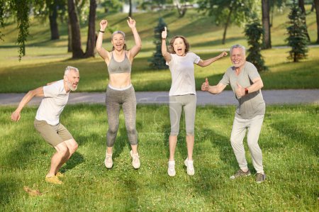 Photo for Group of healthy runners team jumping in the air at city park during morning training expressing happiness, enjoying workout - Royalty Free Image