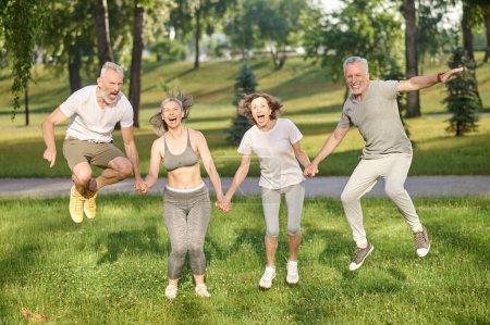 Photo for Group of healthy runners team jumping in the air at city park during morning training expressing happiness, enjoying workout - Royalty Free Image