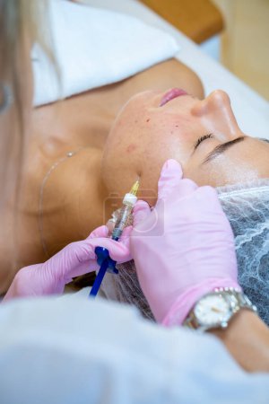 Téléchargez les photos : Cosmétologue méconnaissable faisant des injections aux femmes visage, traitement de la peau dans une clinique esthétique. - en image libre de droit
