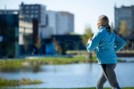Photo for Healthy lifestyle. Woman in blue blazer running in th morning park - Royalty Free Image
