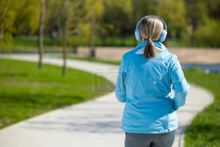Photo for Jogging. Woman in blue blazer listening to the music and jogging - Royalty Free Image