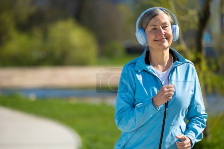 Photo for Morning run. Smiling woman in blue blazer running in the park - Royalty Free Image