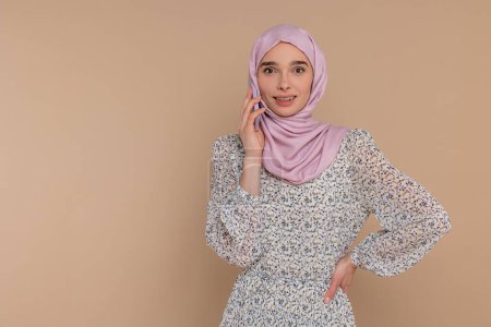 Foto de Llamada telefónica. Mujer joven en hijab rosa hablando por teléfono - Imagen libre de derechos