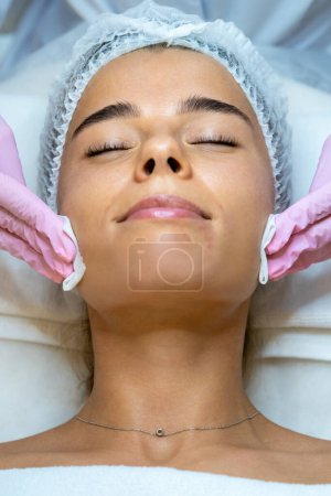 Photo for Unrecognizable cosmetologist doing beauty face procedures or treatment to woman client in aesthetic medicine clinic. - Royalty Free Image