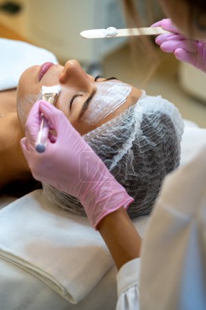 Téléchargez les photos : Esthéticienne professionnelle méconnaissable faisant des procédures de soins de la peau à la cliente. - en image libre de droit