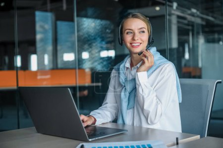 Foto de Trabajando. Mujer joven trabajando en la oficina y escribiendo en un ordenador portátil - Imagen libre de derechos