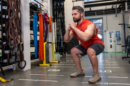 Téléchargez les photos : Homme athlétique échauffement et étirement des jambes faire des redressements assis avant l'entraînement fitness gym, soins du corps, mode de vie sain. - en image libre de droit
