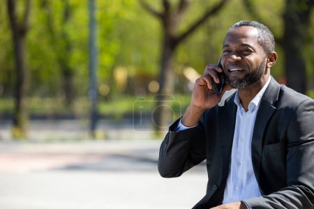 Téléchargez les photos : Bonne affaire. Homme d'affaires afro-américain parlant au téléphone et ayant l'air excité - en image libre de droit