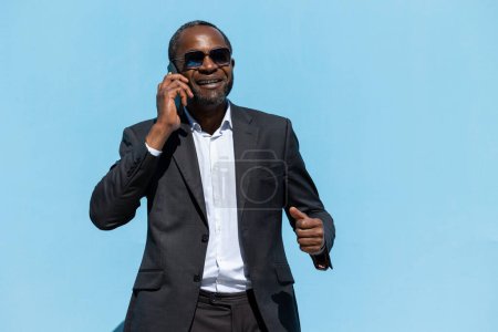 Foto de Buen trato. Hombre de negocios afroamericano hablando por teléfono y mirando emocionado - Imagen libre de derechos