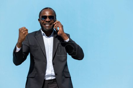 Foto de Llamada telefónica. Hombre de negocios afroamericano hablando por teléfono y mirando emocionado - Imagen libre de derechos