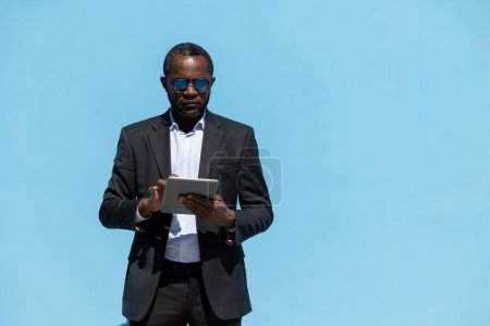 Téléchargez les photos : Un homme d'affaires prospère. Elégant homme à la peau foncée avec un ordinateur portable dans les mains - en image libre de droit