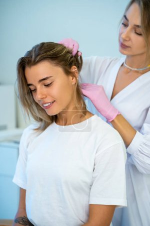 Photo for Blonde doctor in protective medical gloves doing hair injection head rejuvenation hair loss treatment. - Royalty Free Image