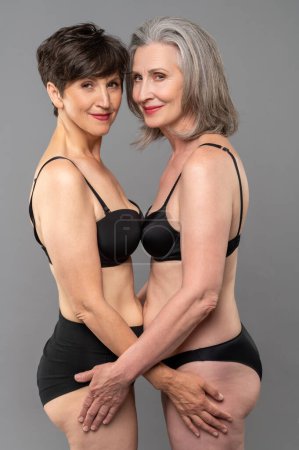 Photo for Closeness. Senior women in black bra and panties standing close - Royalty Free Image