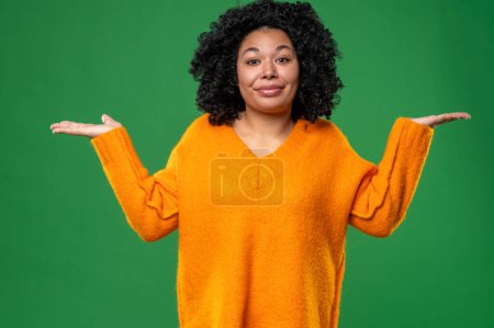 Téléchargez les photos : Heureux. Jeune femme aux cheveux bouclés en orange sur fond vert - en image libre de droit