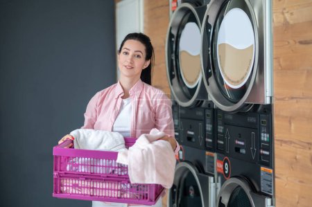 Téléchargez les photos : Woman housewife came to laundry, holding basket with dirty clothing. - en image libre de droit