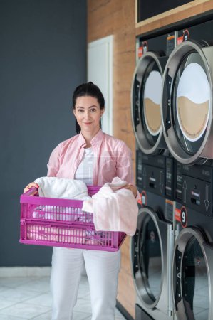 Photo for Woman housewife came to laundry, holding basket with dirty clothing. - Royalty Free Image