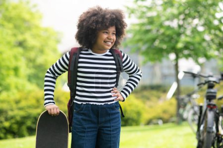 Photo for Young girl having fun standing with skateboard at summer outdoor schoolgirl enjoying skateboarding in the park. - Royalty Free Image