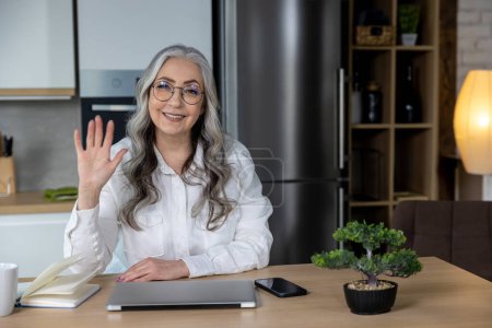 Photo for Greeting. Elegant business woman having a video call and waving her hand - Royalty Free Image