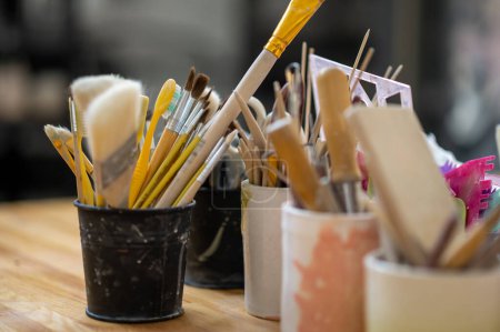 Téléchargez les photos : Outils de poterie sur table en bois dans un studio de création, équipement de fabrication avec des pinceaux. - en image libre de droit