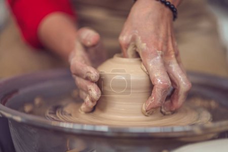 Foto de Mujer irreconocible trabajando en la rueda de cerámica y esculpir olla de barro. - Imagen libre de derechos