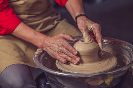Photo for Unrecognizable woman working on pottery wheel and sculpting clay pot. - Royalty Free Image