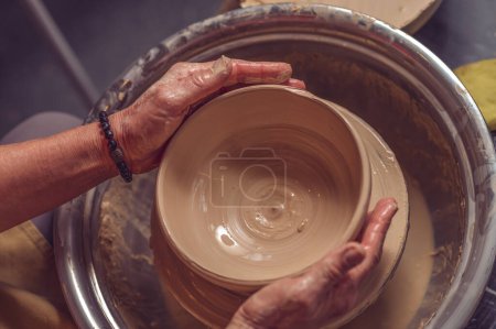Foto de Mujer alfarera irreconocible creando hermoso plato con arcilla, haciendo obras de arte con sus manos. - Imagen libre de derechos