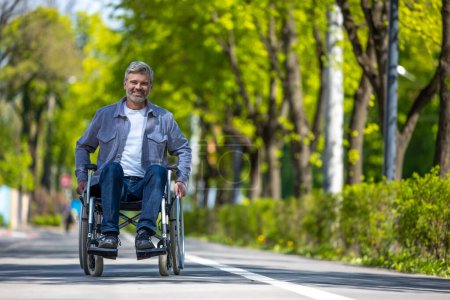 Foto de Hombre discapacitado en silla de ruedas con ropa casual cabalgando en la calle, ocio al aire libre para chico discapacitado. - Imagen libre de derechos