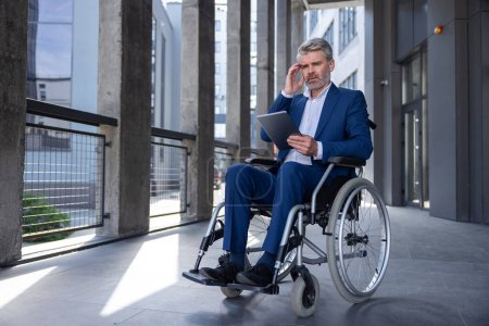 Photo for Pensive thoughtful business man in wheelchair with tablet pc in hands, browsing web, using mobile device for work outdoors, thinking over new project. - Royalty Free Image