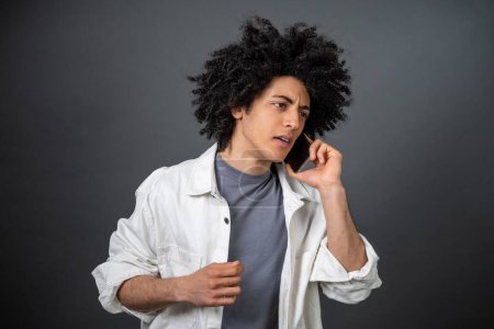 Photo for Troubles. Curly-haired young man talking on the phone and looking stressed - Royalty Free Image