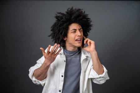 Photo for Troubles. Curly-haired young man talking on the phone and looking stressed - Royalty Free Image