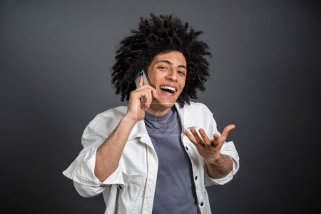 Photo for Excited. Young dark-haired man talking on the phone and looking excited - Royalty Free Image
