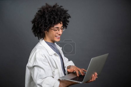 Photo for Digital nomad. Young freelance with a laptop on grey background - Royalty Free Image