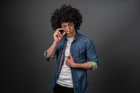 Foto de Un tipo de moda. Joven chico de moda en camisa de mezclilla en un bakcground gris - Imagen libre de derechos