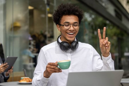 Foto de Buenos días. Joven hombre de negocios teniendo una videollamada y tomando café por la mañana - Imagen libre de derechos