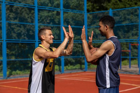 Photo for Athletic men friends on basketball court, giving high five. - Royalty Free Image