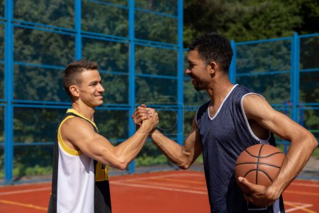 Foto de Hombres atléticos amigos en la cancha de baloncesto, apretón de manos. - Imagen libre de derechos