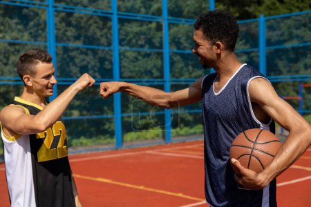 Photo for Athletic men friends on basketball court, fist bump. - Royalty Free Image
