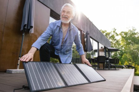 Foto de Hombre caucásico con tecnología de innovación de paneles solares energía alternativa en el porche de la casa. - Imagen libre de derechos