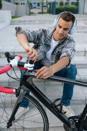Téléchargez les photos : Réparation. Jeune homme réparant un vélo assis sur les marches - en image libre de droit