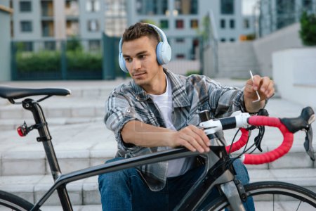 Photo for Repair. Young man repairing a bike while sitting on the steps - Royalty Free Image
