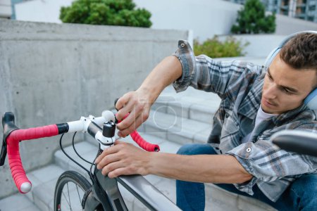 Téléchargez les photos : Réparation de vélos. Un jeune homme souriant répare un problème avec le vélo - en image libre de droit