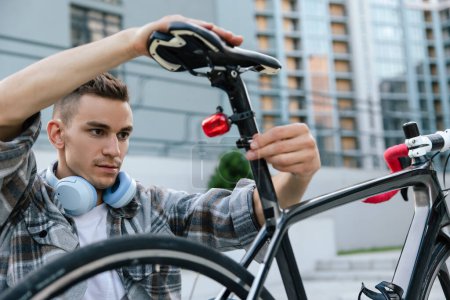 Téléchargez les photos : Réparation de vélos. Homme en chemise à carreaux réparer un vélo - en image libre de droit