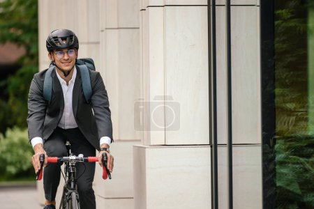 Téléchargez les photos : Demain matin. Jeune homme d'affaires souriant sur un vélo - en image libre de droit