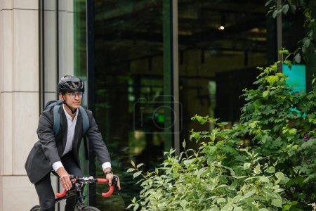 Téléchargez les photos : Au bureau. Jeune manager se rendant au bureau à vélo - en image libre de droit