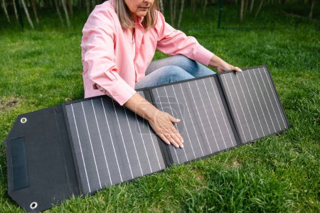 Foto de Mujer irreconocible sosteniendo panel solar en el jardín. - Imagen libre de derechos