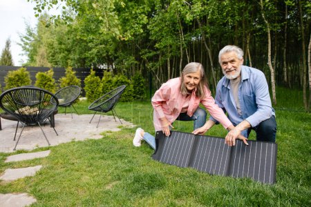 Photo for Smiling man and woman showing solar charger, power battery, flexible solar panel. - Royalty Free Image