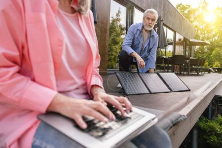 Foto de Mujer irreconocible y el hombre que trabaja en el ordenador portátil utilizando el panel solar al aire libre. - Imagen libre de derechos