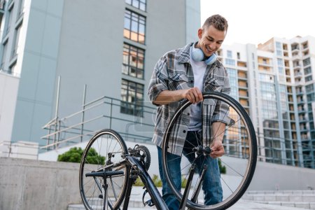 Téléchargez les photos : Problème avec un vélo. Jeune homme fixer un problème avec le pneu - en image libre de droit